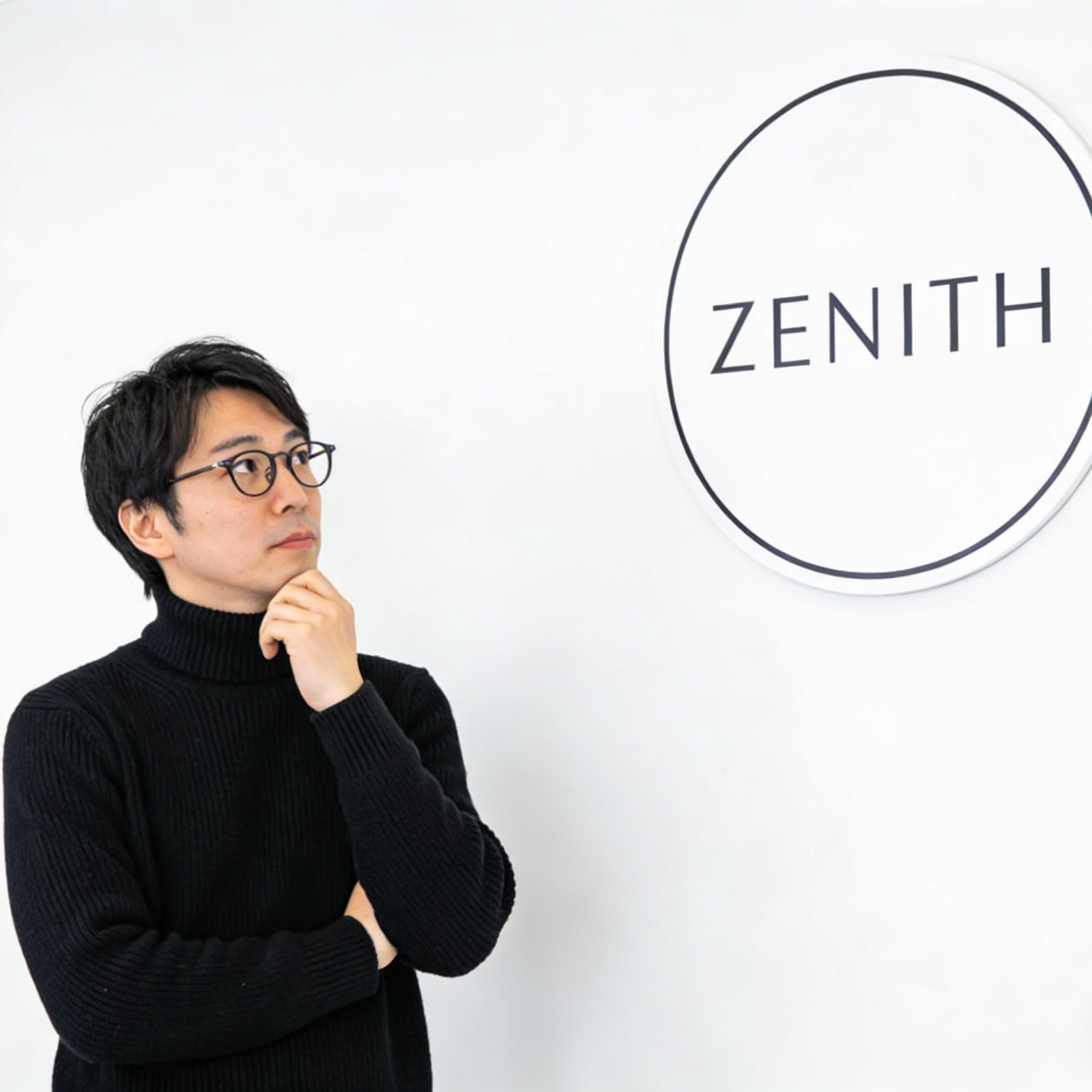 A minimalist brand identity scene with a person looking at a Zenith sign on a white wall