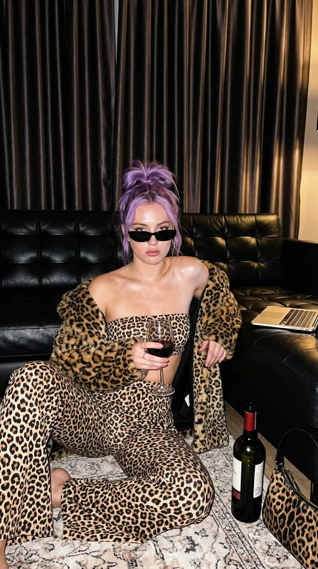 AI-generated luxury evening portrait of a woman in leopard print holding a glass of red wine under warm amber candlelight in a moody, aspirational interior setting variation 1